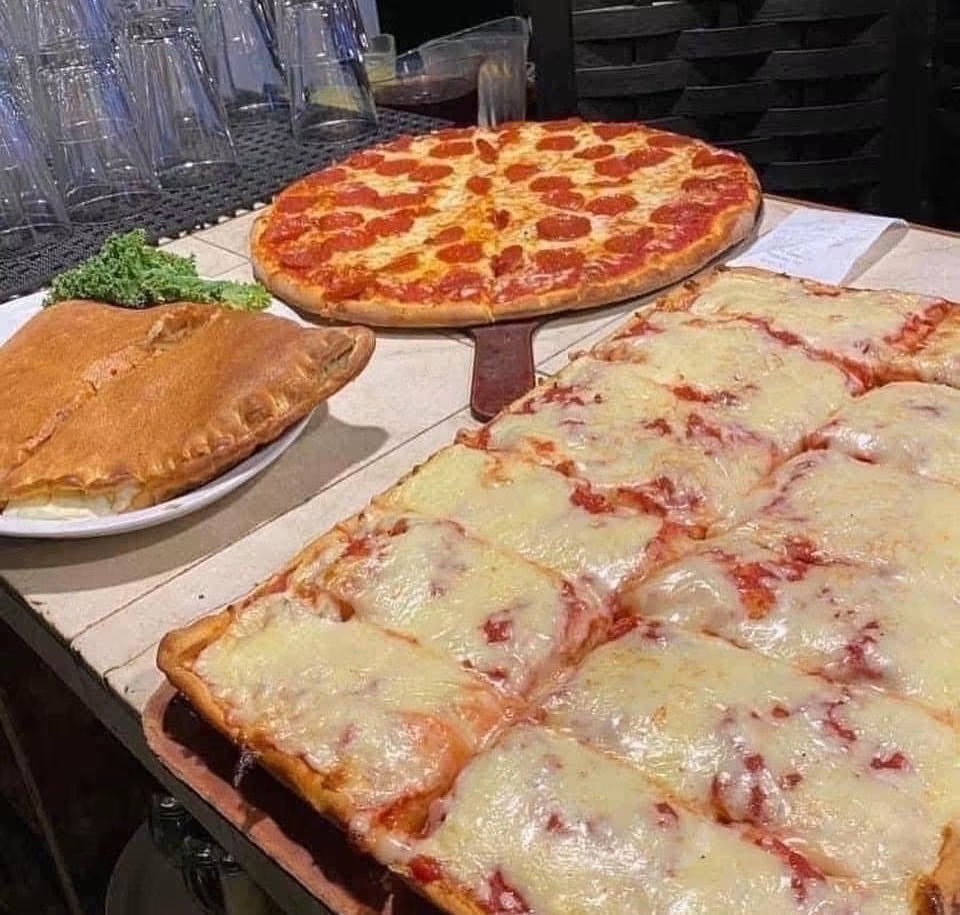 Two pizzas, one with pepperoni and cheese, and the other with cheese and tomato sauce, along with a calzone on a table.