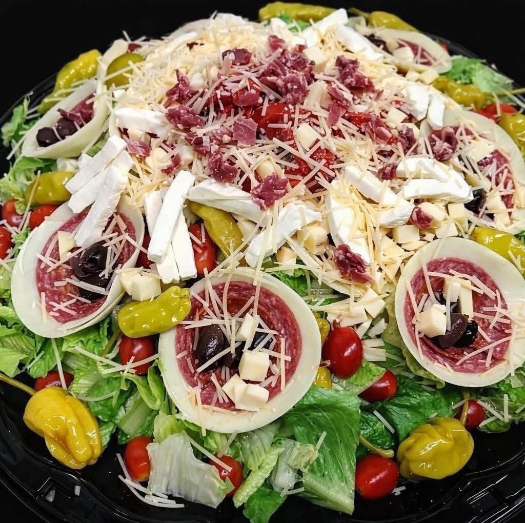 Fresh salad with lettuce, cherry tomatoes, sliced onions, yellow peppers, and shredded cheese, topped with sliced radishes and cheese shavings.