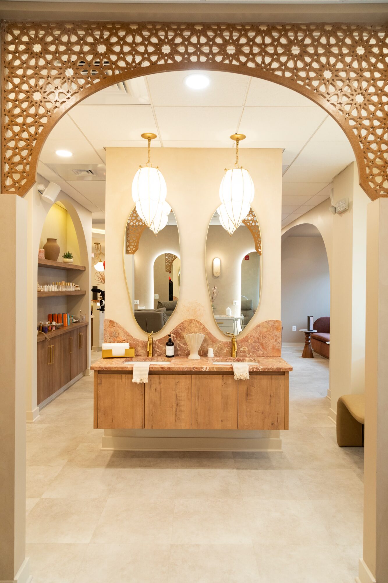Interior view of a reception area with a wooden desk, decorative arches, hanging pendant lights, and seating in the background.