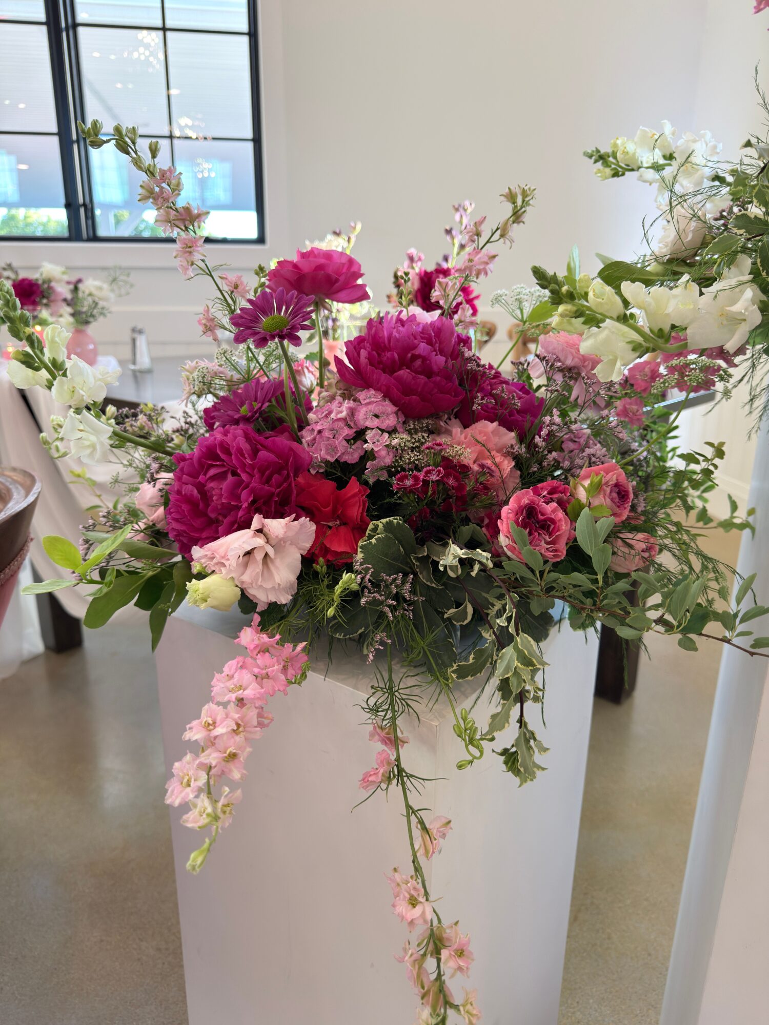 A colorful bouquet of pink, purple, and white flowers with green foliage, arranged in a tall vase.