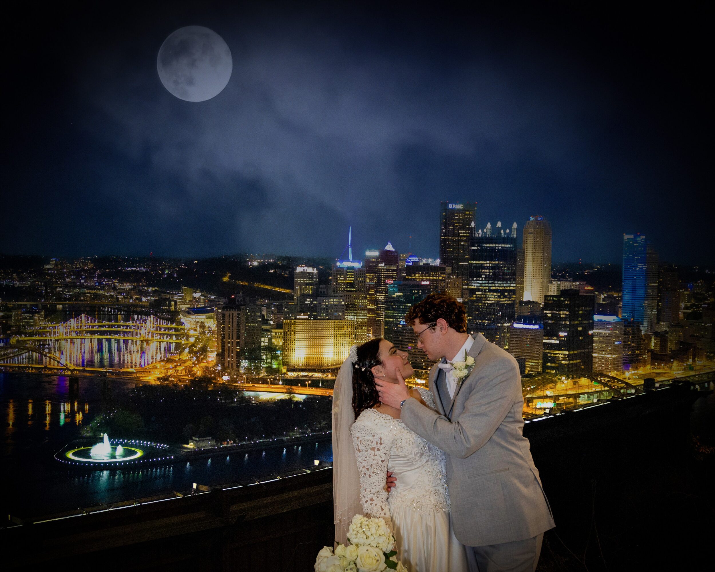 A couple kissing at night with a city skyline and full moon in the background.
