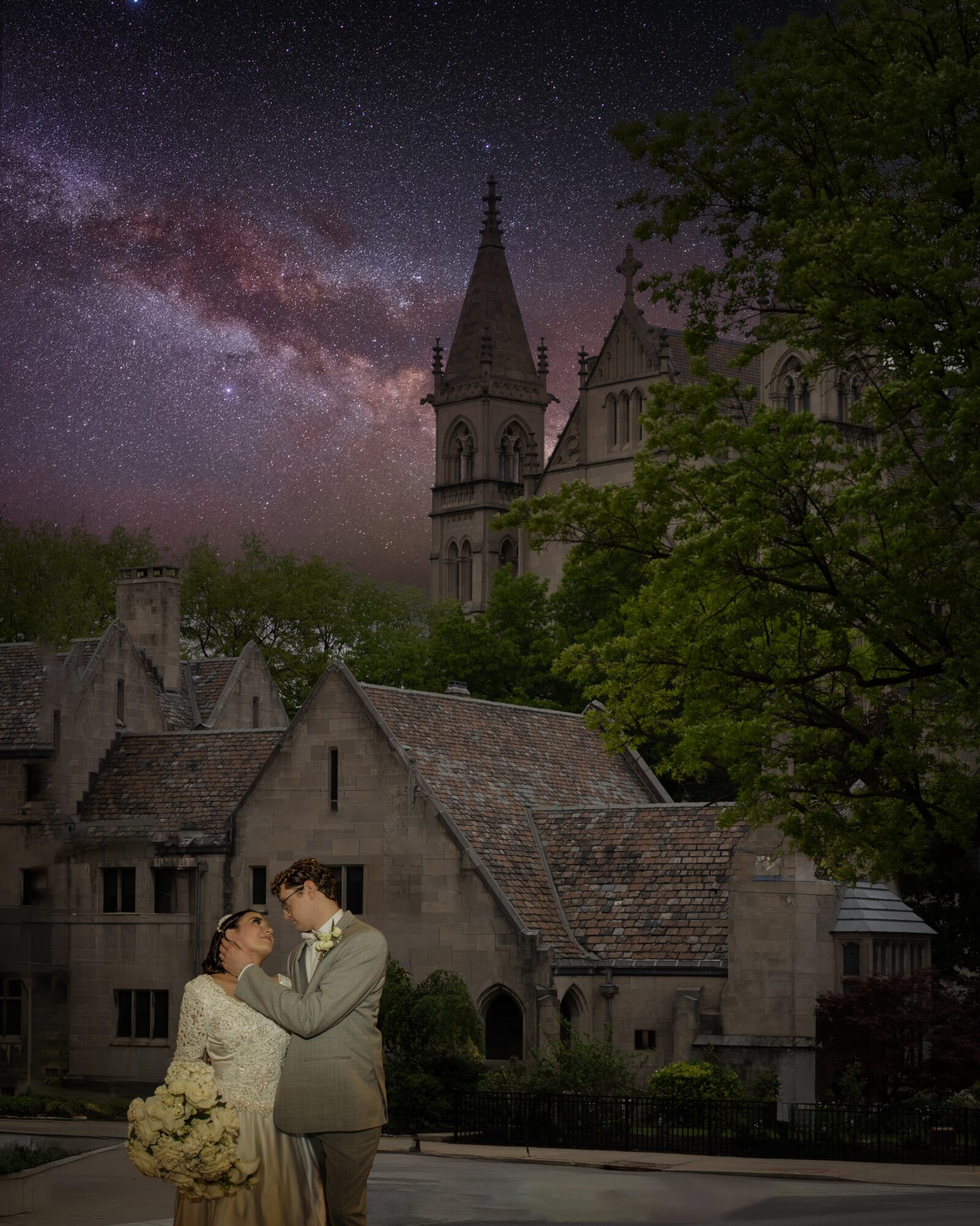 Couple embracing in front of historic buildings with church steeple under starry night sky