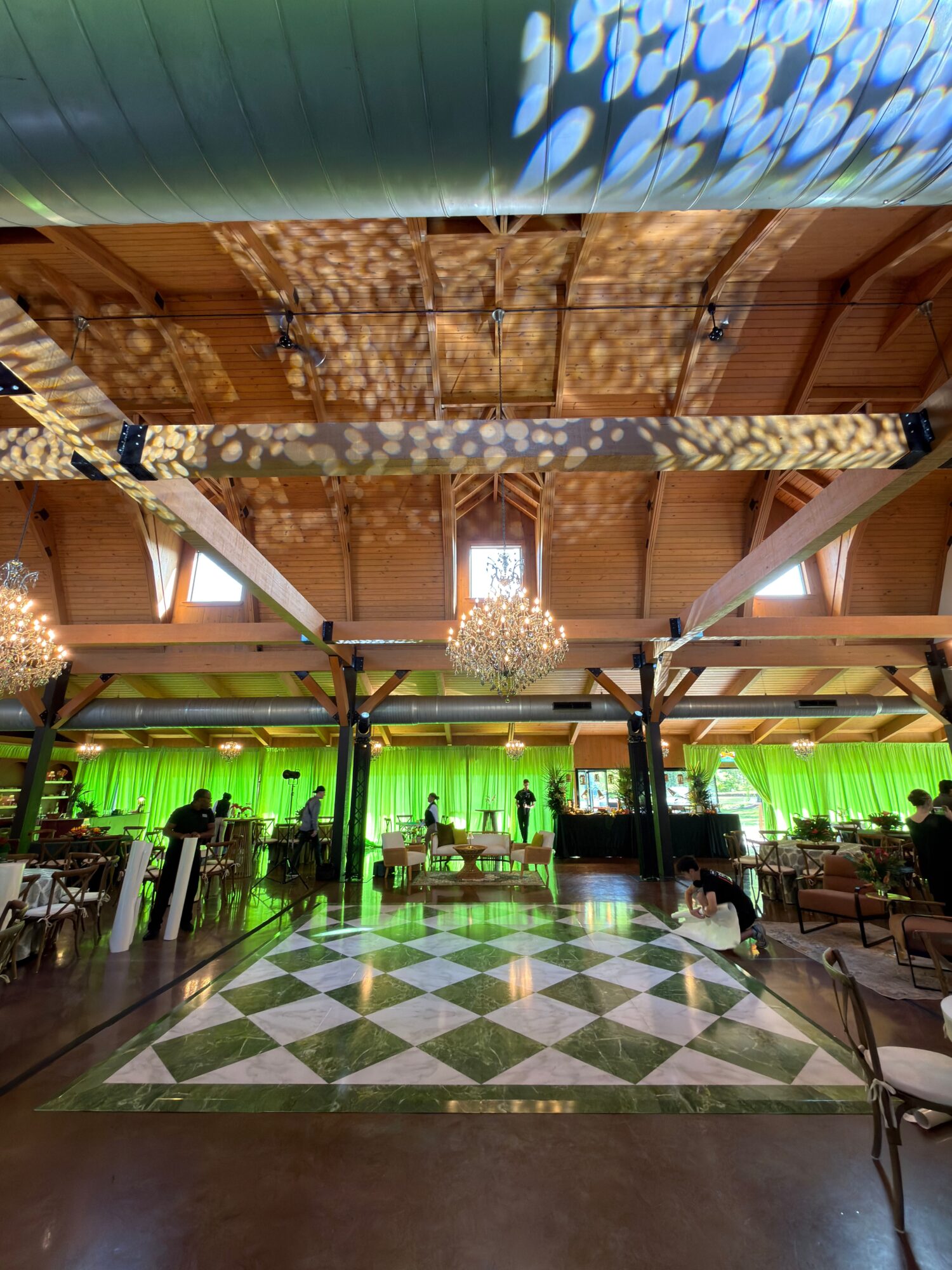 Indoor space with a green-lit stage, patterned floor, and various equipment, viewed from a low angle.