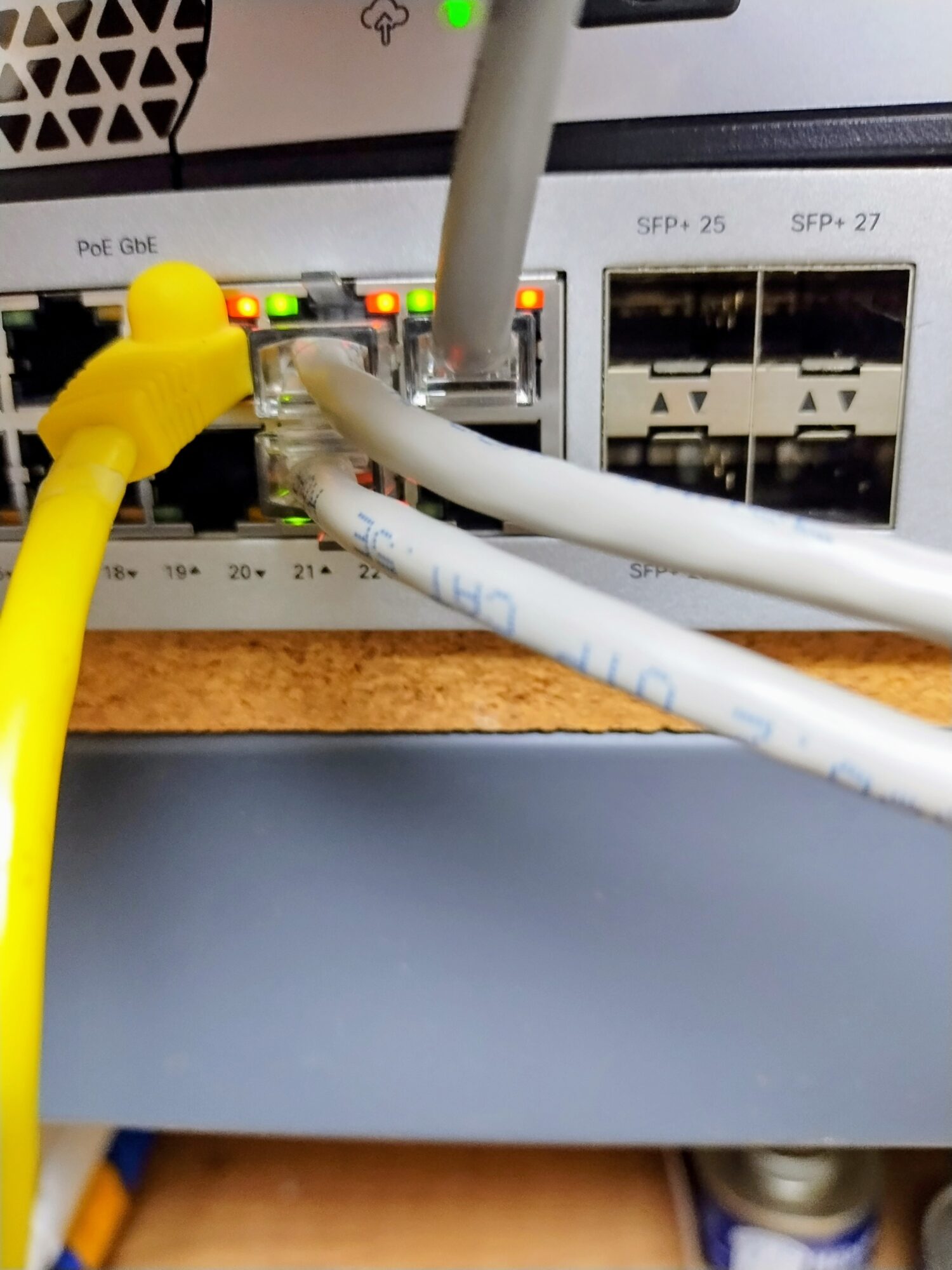Network cables plugged into a switch with indicator lights, on a desk surface.