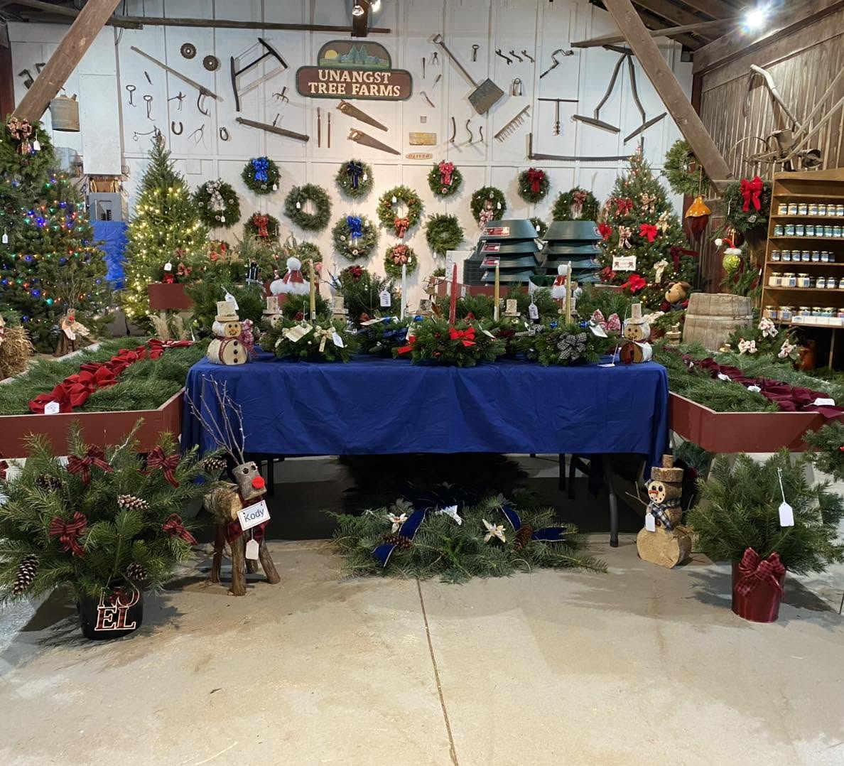 Indoor Christmas display with wreaths, ornaments, and holiday decorations on walls and tables, including reindeer and gift boxes.