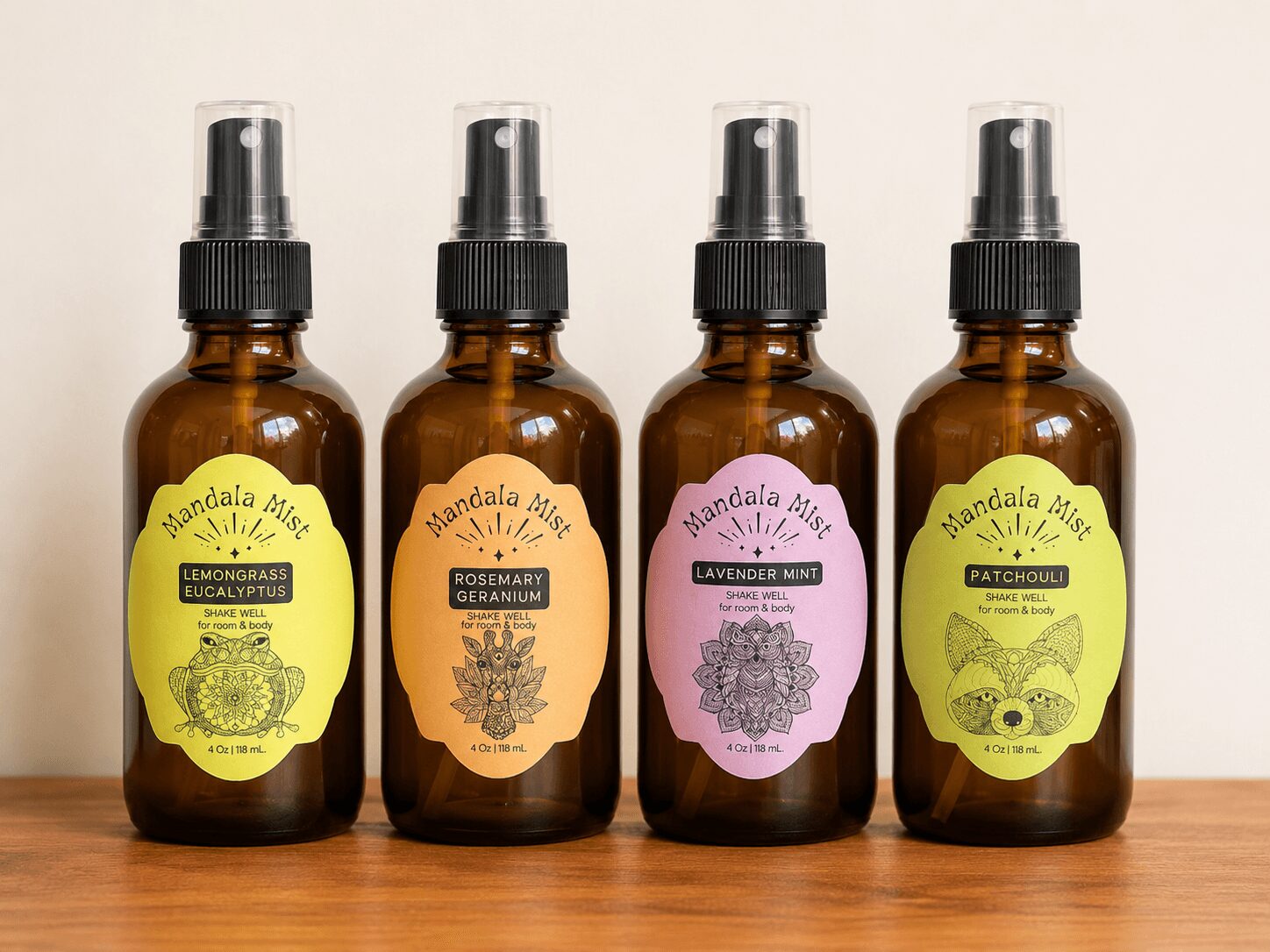 Four amber spray bottles with black caps and colorful labels on a wooden surface, each labeled with different scents.