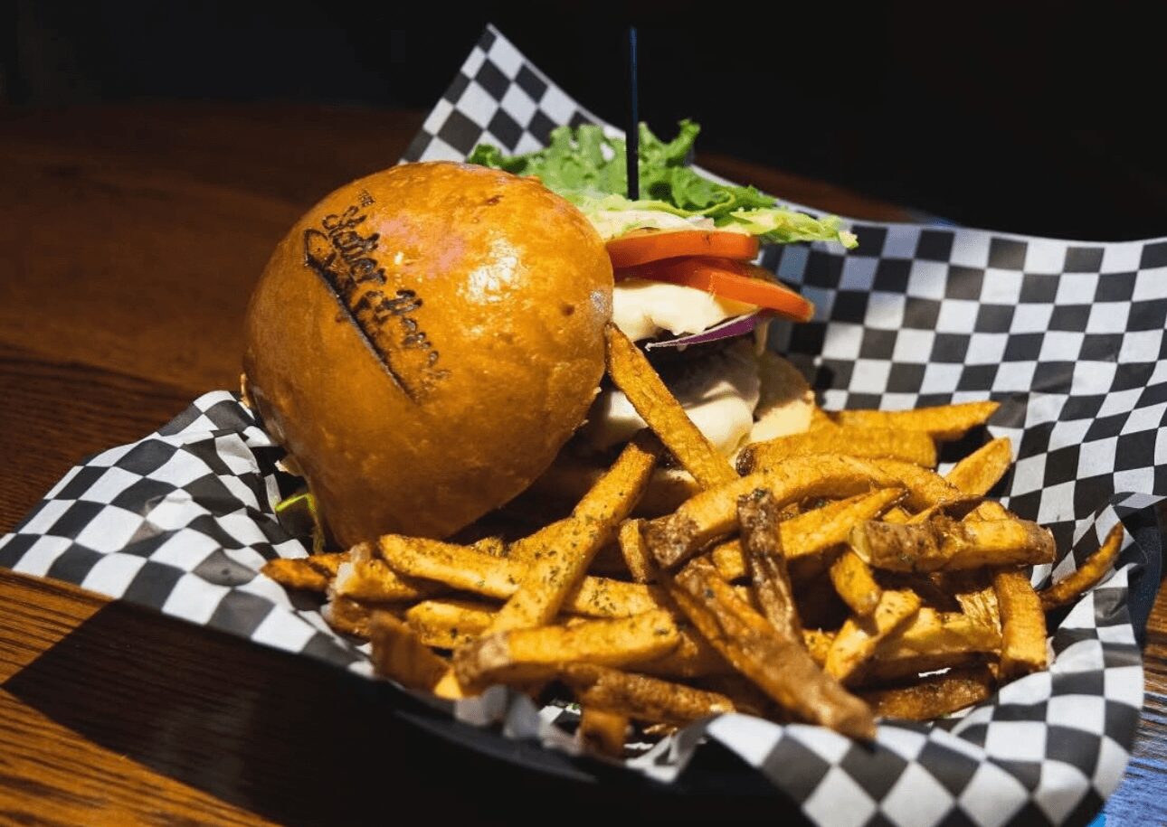 Fried chicken with fries on checkered paper, garnished with lettuce and vegetables, served on a wooden table.