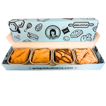 Open box with four pastries, each in separate compartments, with decorative blue packaging featuring illustrations of baked goods.