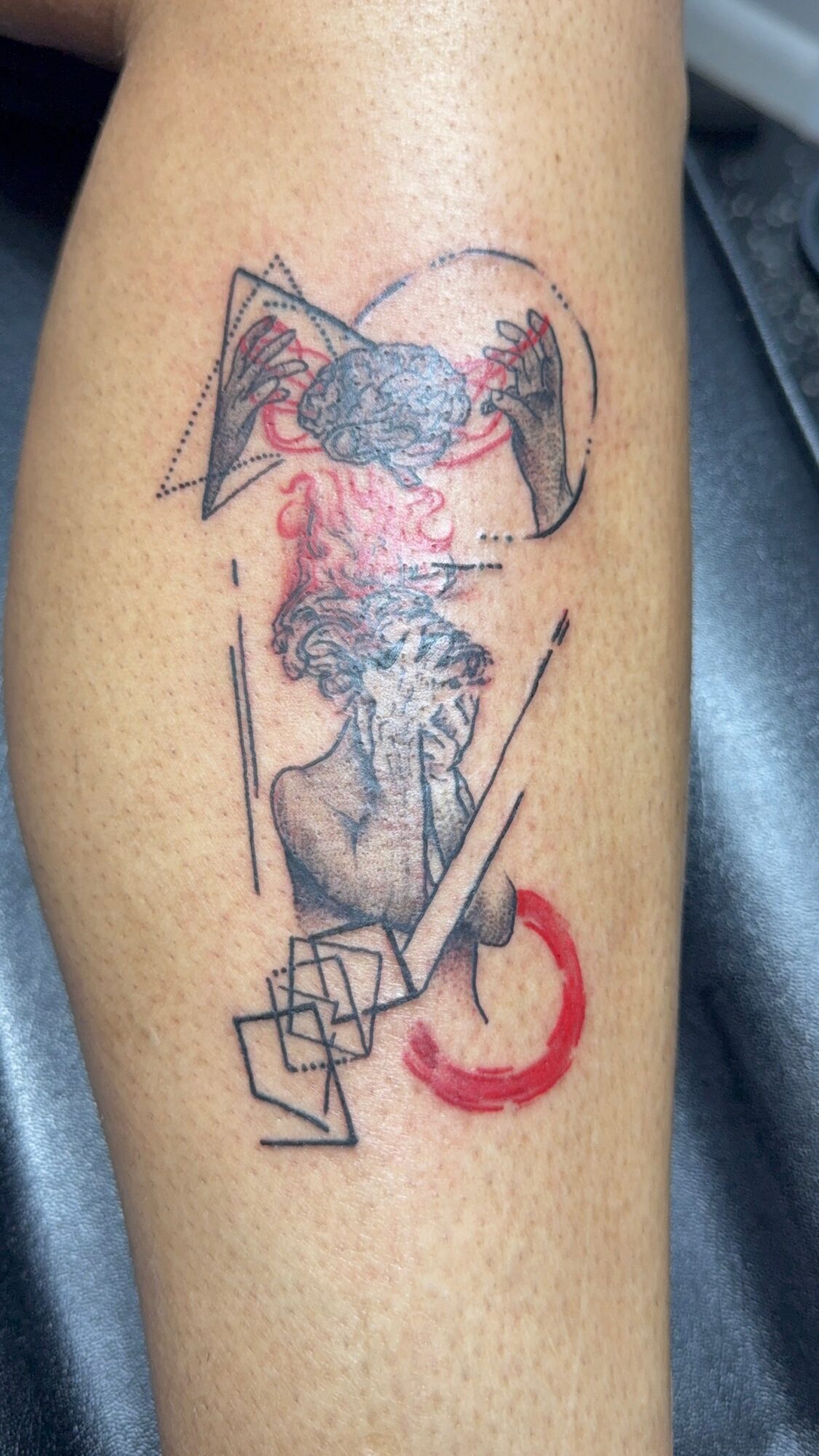 Tattoo of a person with a beard, geometric shapes, and red accents on skin.