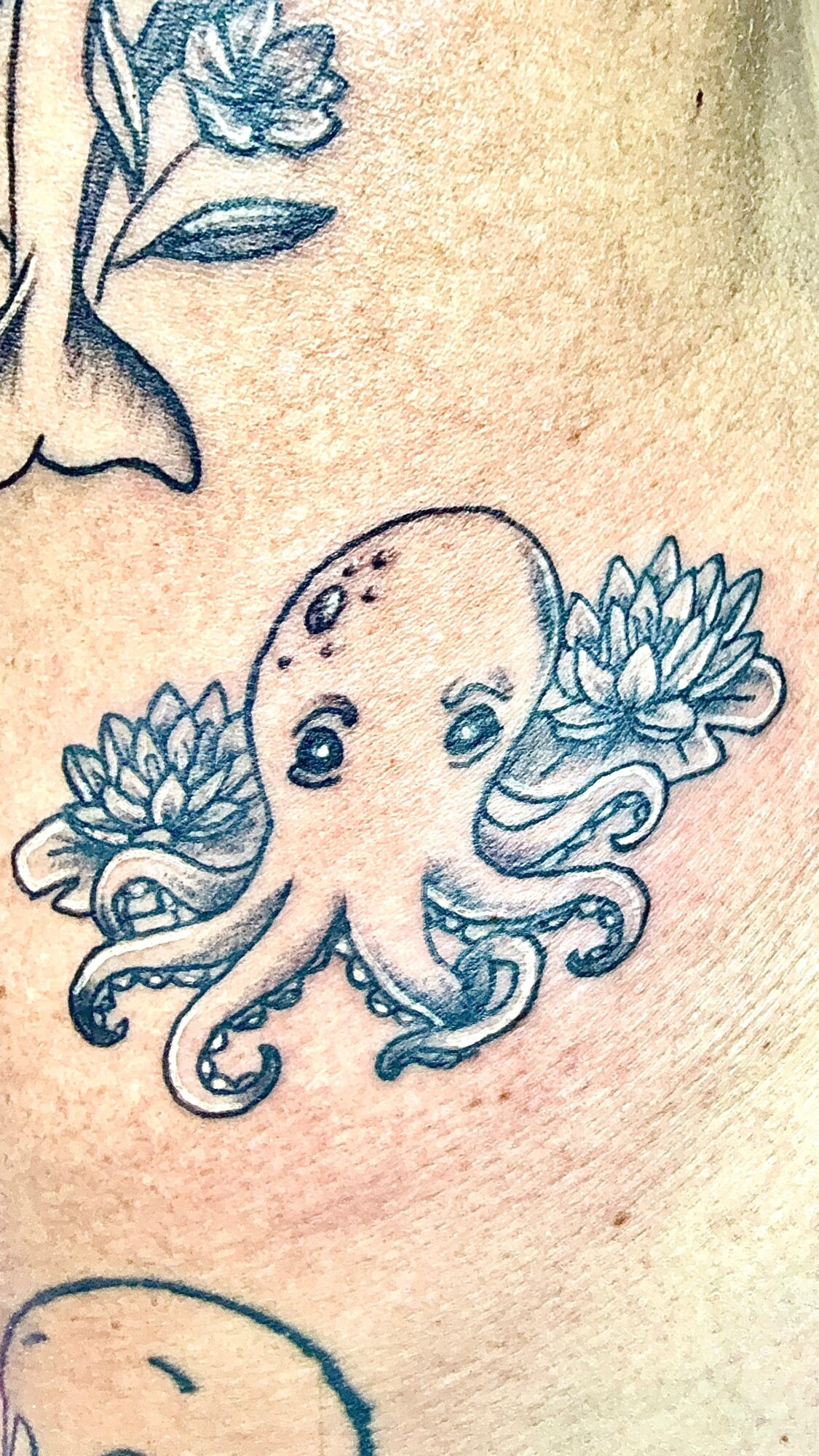 Tattoo of an octopus with flowers on its head, detailed with large eyes and tentacles, on skin.