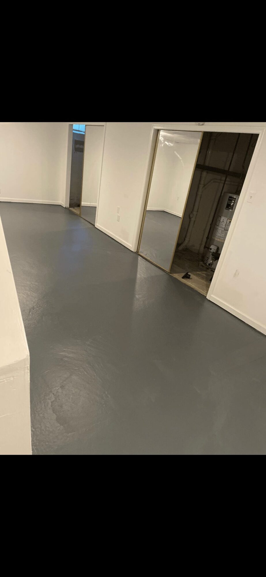 Empty room with gray floor, white walls, and an open doorway leading to another space.