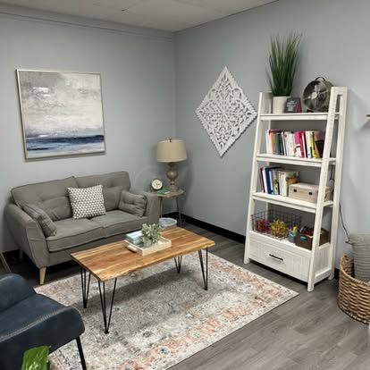 Living room with gray sofa, wooden coffee table, white bookshelf, and decorative wall art, with a rug and a basket.