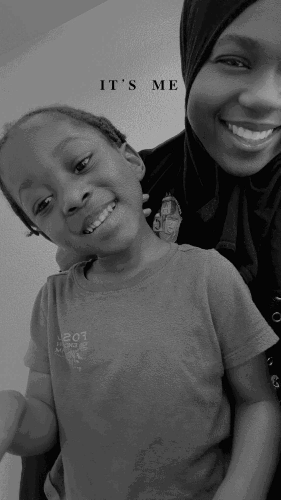 A smiling woman and child pose together, with part of a sign visible in the background.