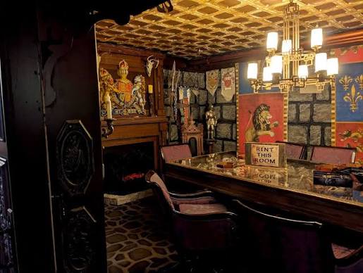 Decorative room with ornate wall art, a chandelier, and a long table with chairs, creating a cozy, vintage atmosphere.