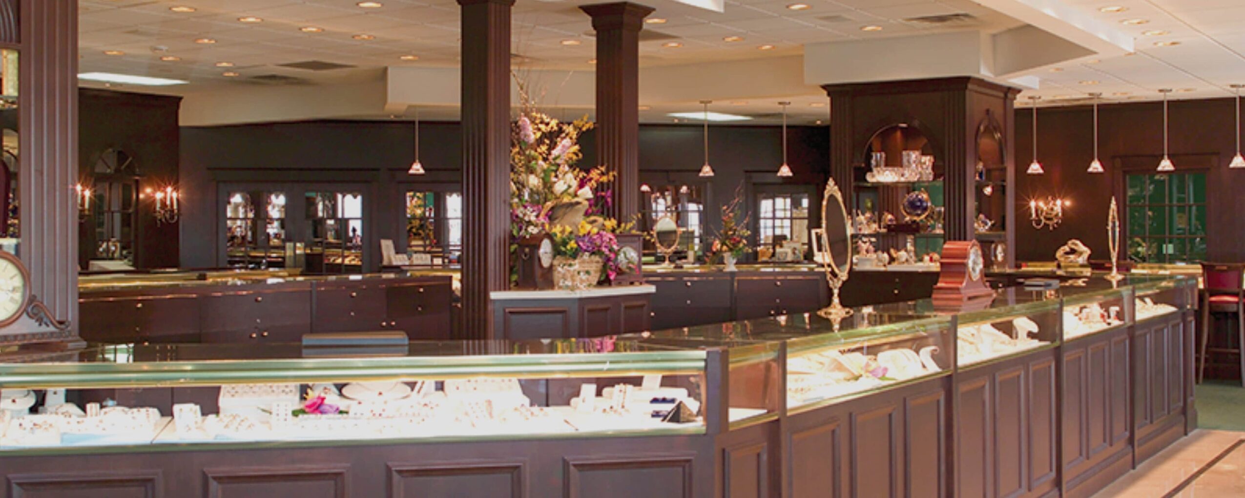 Ice cream display counter in a restaurant with dark wood decor and floral arrangements.