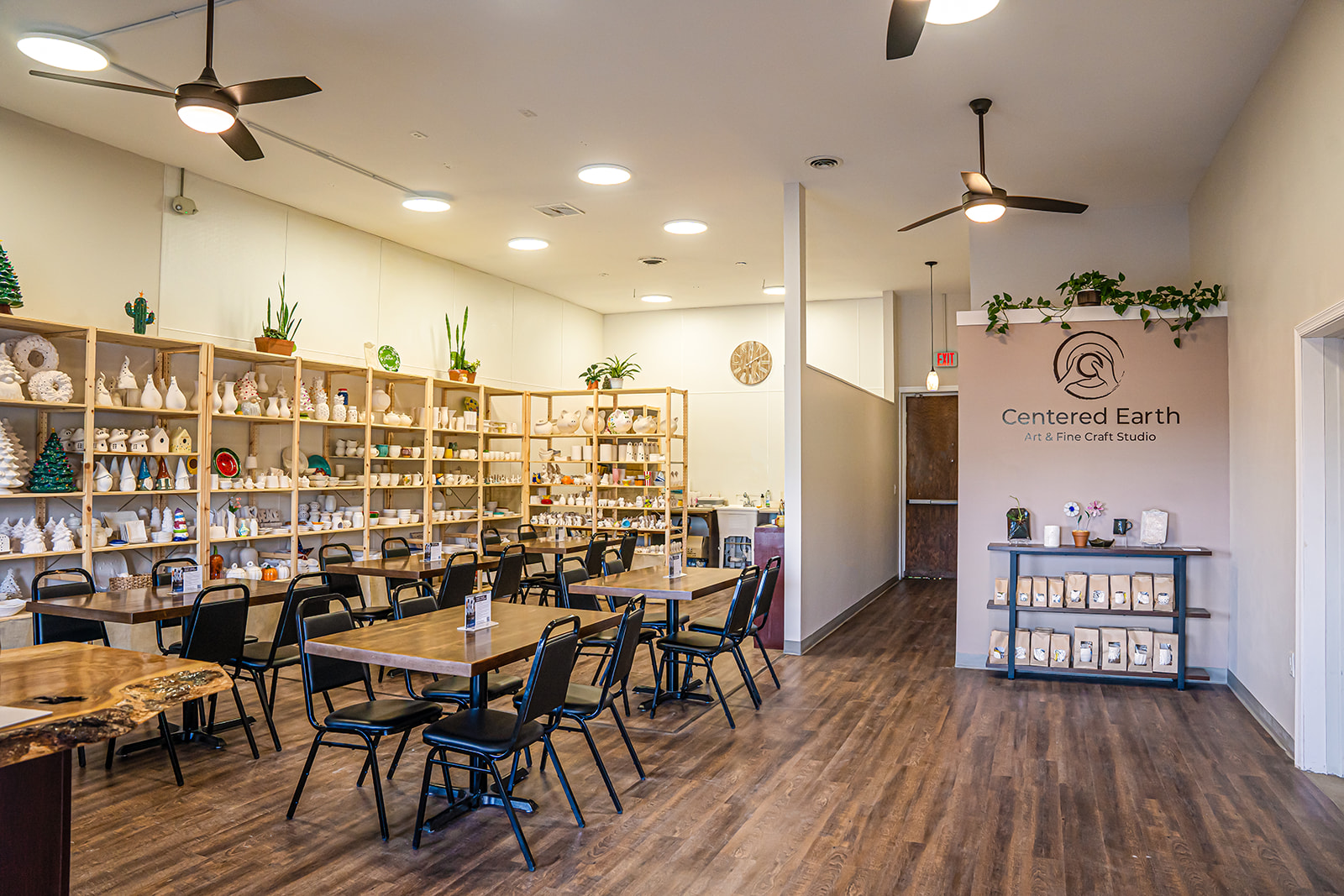Room with shelves of crystals and plants, tables and chairs, wooden floor, and a sign reading 'Centered Earth'.