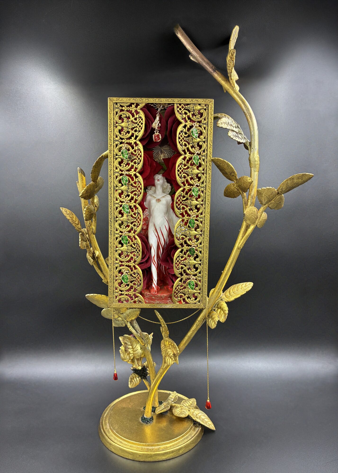 Decorative gold-colored frame with a central figure, surrounded by gold leaves and branches, on a dark background.