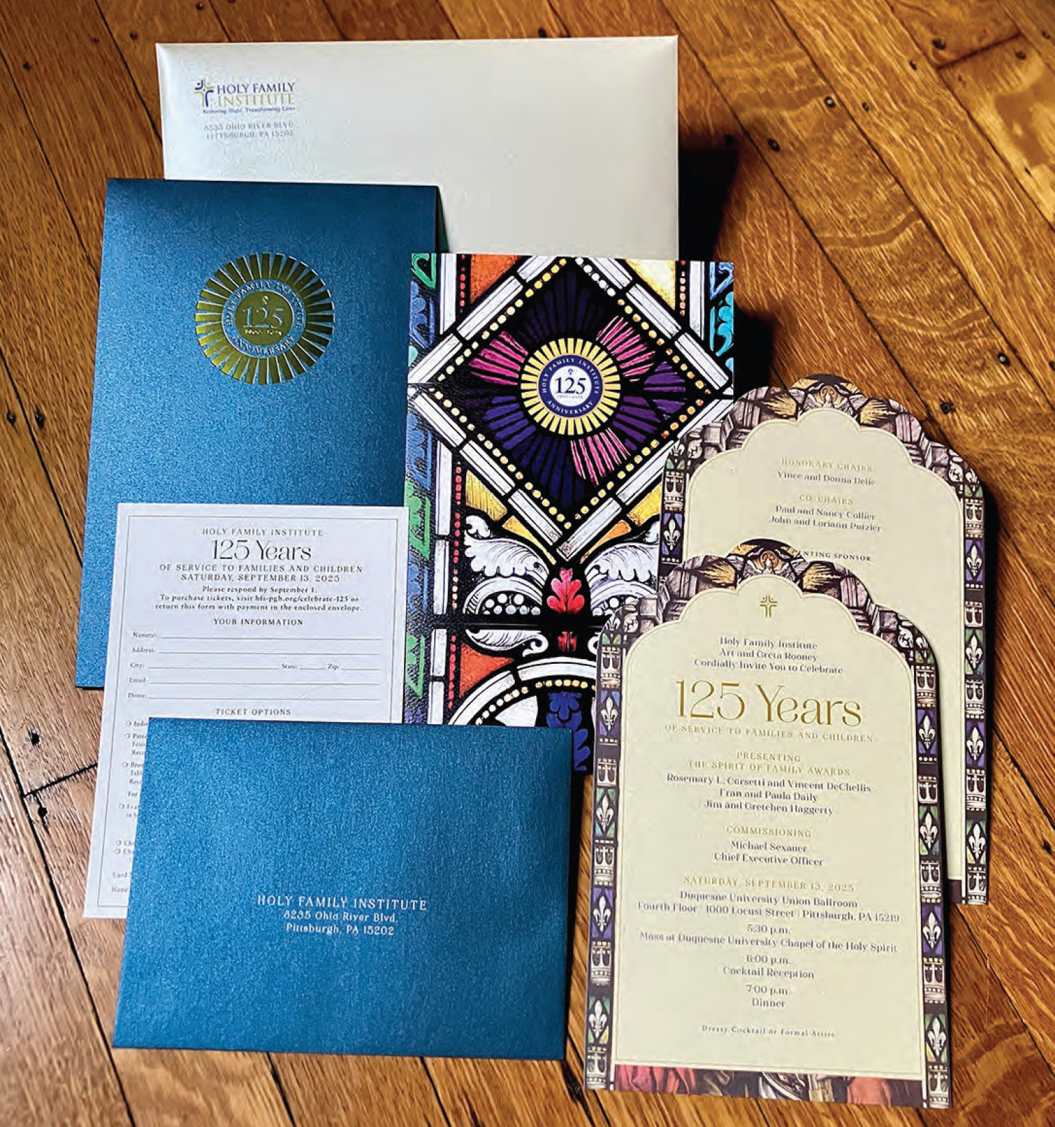 Celebration invitation and program cards for 125 years, with decorative borders, on a wooden surface.