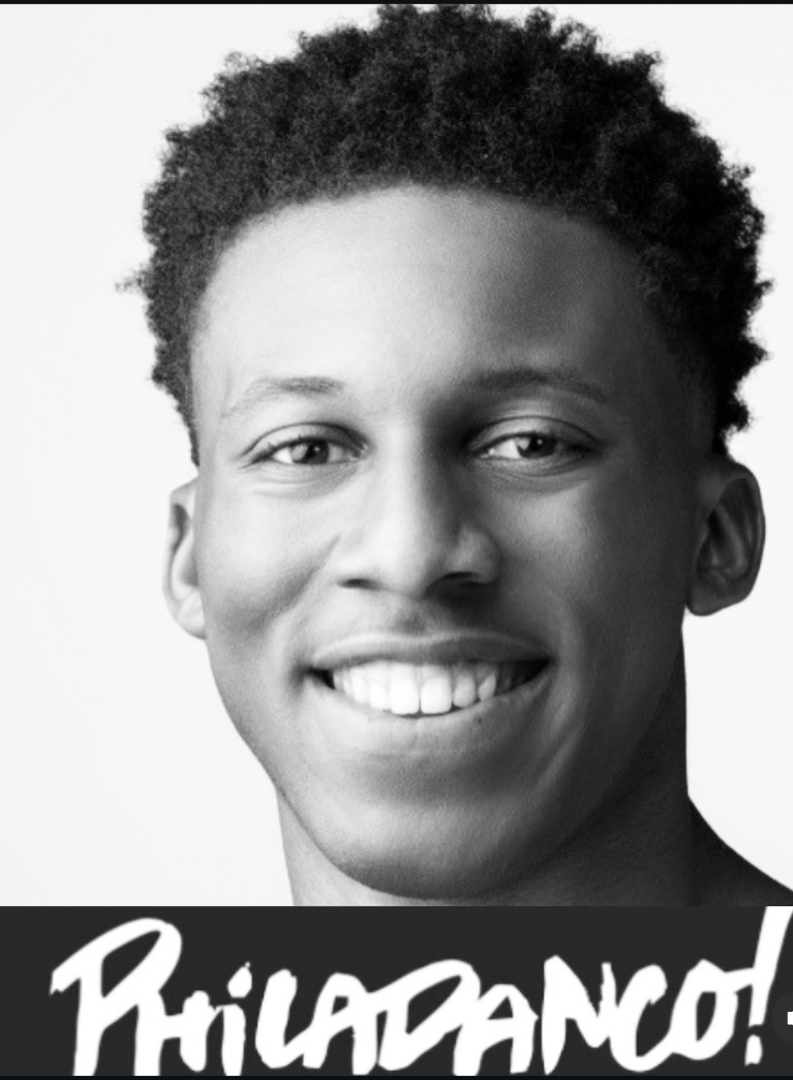 Young man with curly hair smiling, black and white photo, close-up portrait.