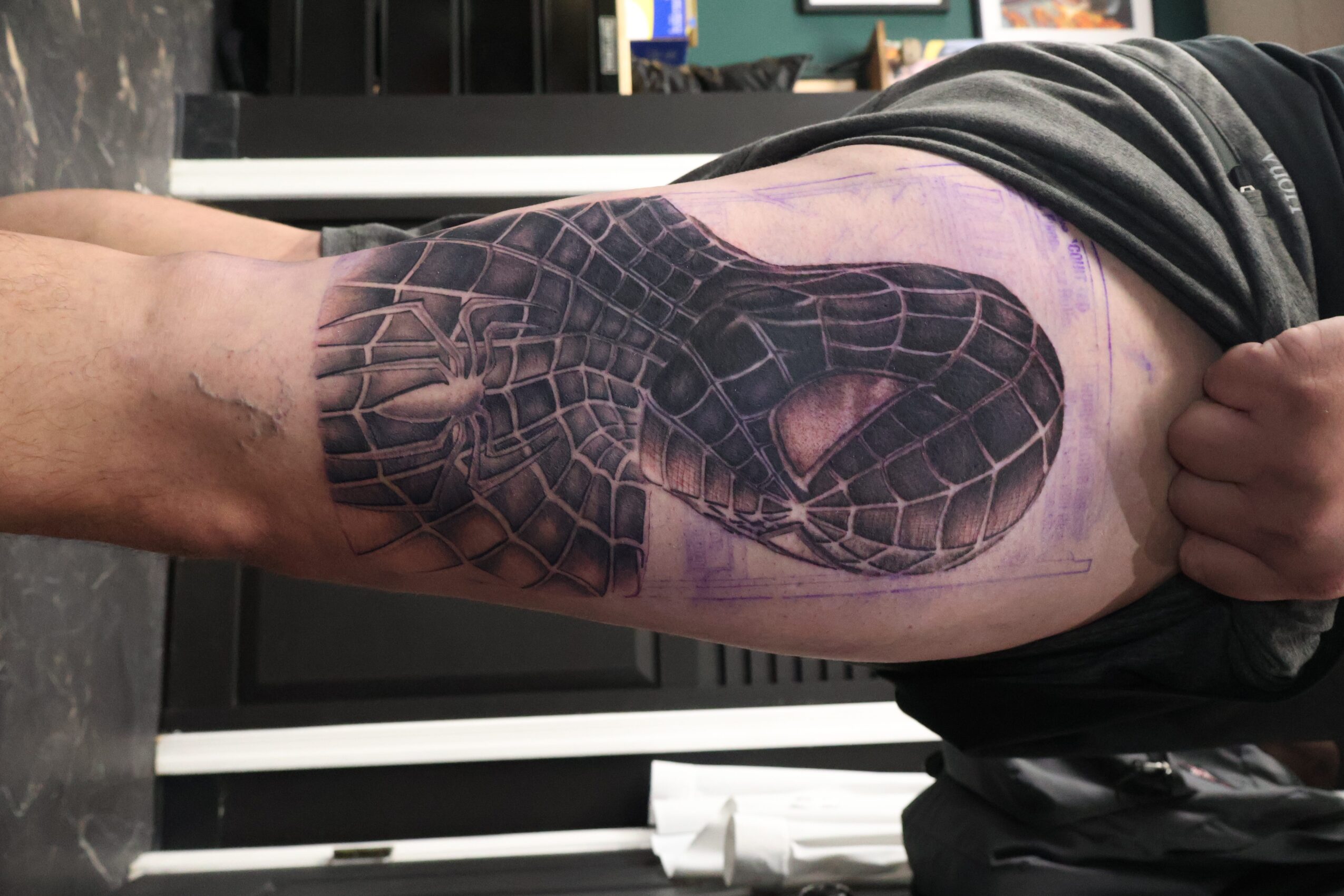 Tattoo of a snake's head on person's thigh, with purple outline and shading, detailed scales and eye.