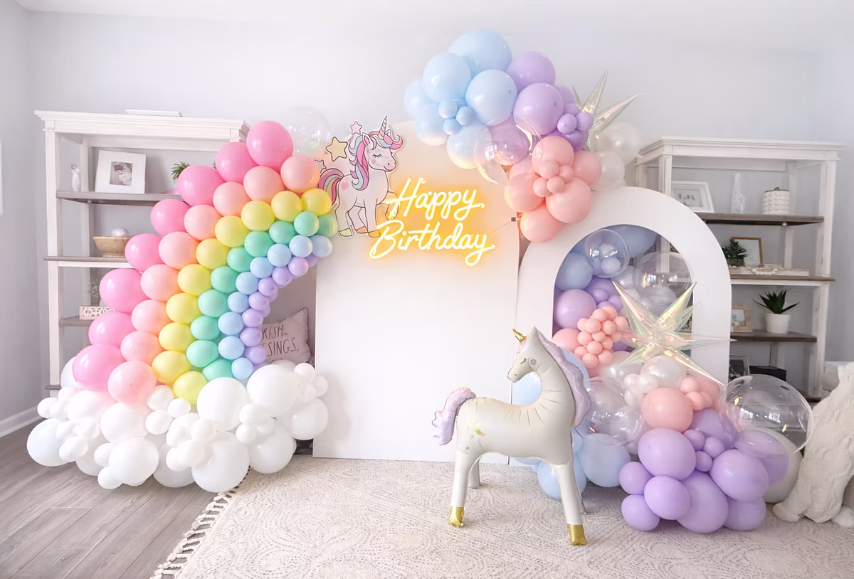 Colorful balloon rainbow with unicorn and birthday sign in a decorated room, celebrating a birthday.