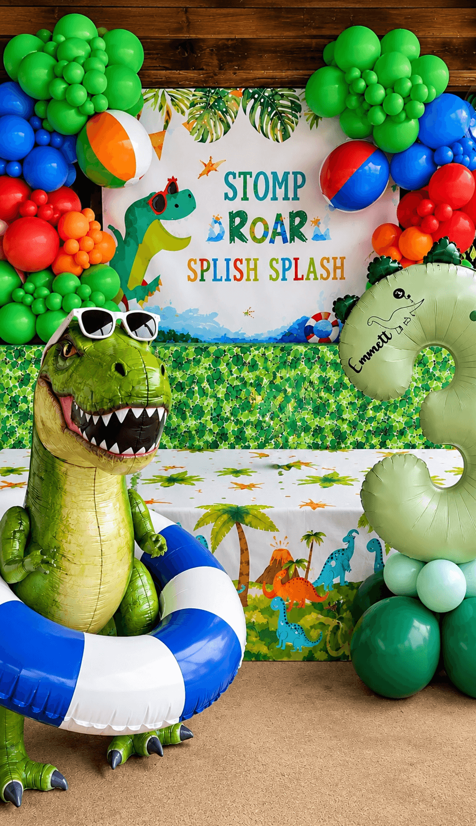 Colorful jungle-themed party backdrop with balloons, plush crocodile, and a sign reading 'Stomp Roar Splash Splash'.