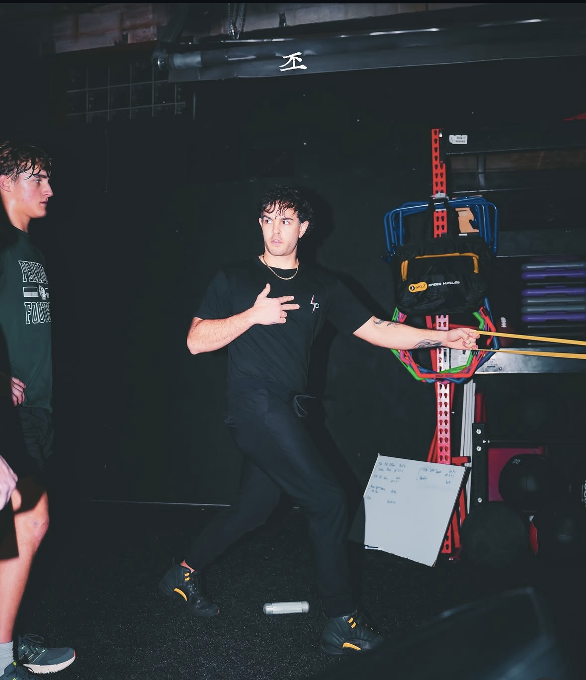 Person holding a yellow stick in a dark room with equipment and another person nearby.